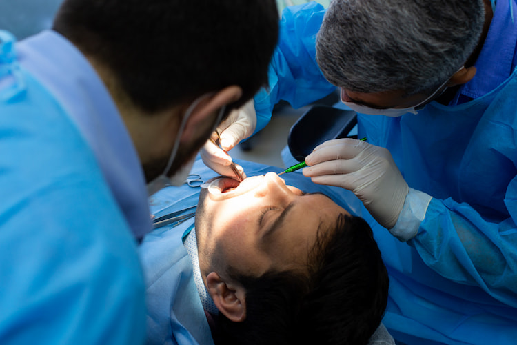 a dentist is performing a surgical gum treatment on a patient. 