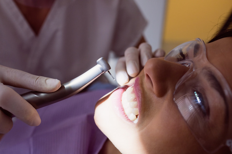 a close-up of a patient receiving dental cleaning from a dentist.