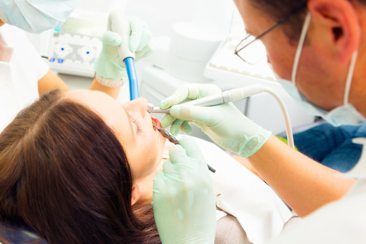 a dentist is using dental tools to clean a patient's teeth professionally. 
