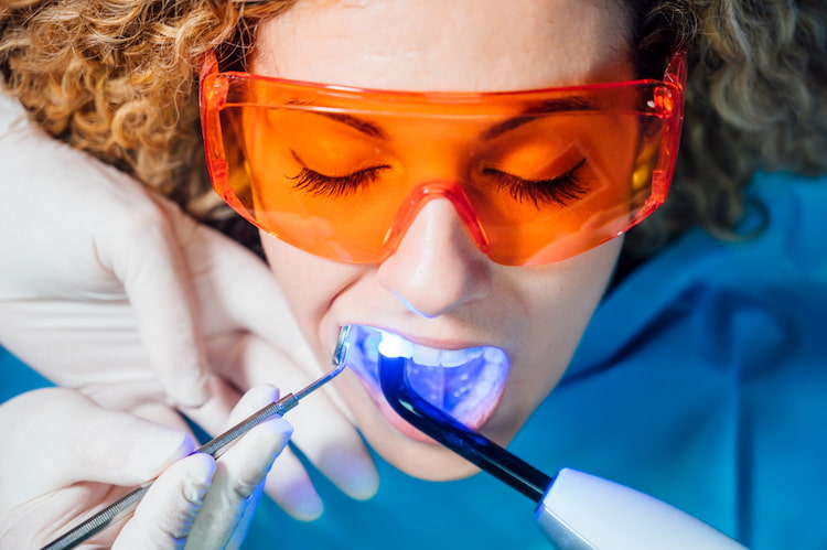 a woman is getting teeth whitening treatment. 