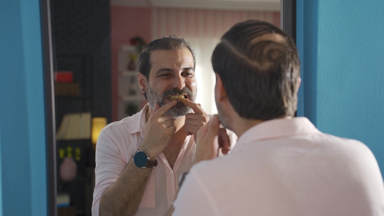 Man looking in the mirror and examining yellowed dental fillings, concerned about discoloration.