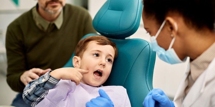 Young boy at a dental clinic with a parent present while a dentist examines a cracked tooth.