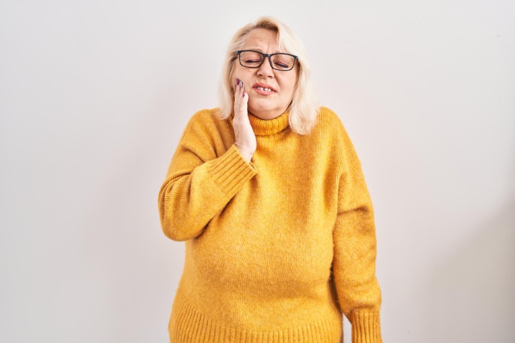 Woman experiencing severe tooth pain, holding her cheek in discomfort, indicating a dental emergency situation