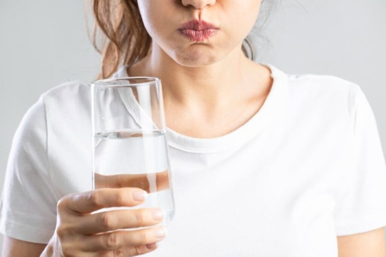 Woman rinsing her mouth with warm water to manage a chipped tooth and reduce discomfort.