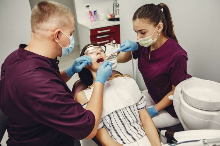Dentist and dental assistant treating a female patient with an emergency chipped tooth in a clinical setting.