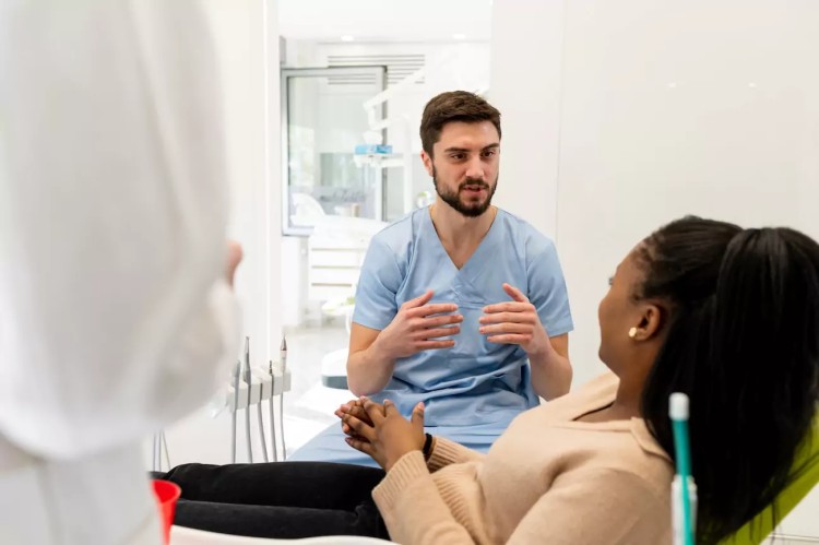 A patient and a dentist discussing treatment in a clinic, using CBT techniques to help overcome dental anxiety during the consultation.