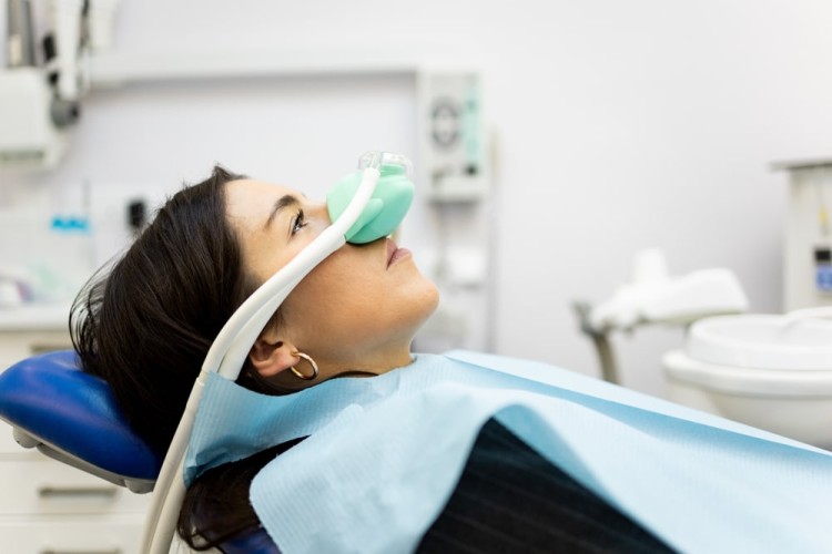 Sedation treatment to overcome dental anxiety being administered through a breathing tube placed over the patient’s face, while the patient appears calm and relaxed.