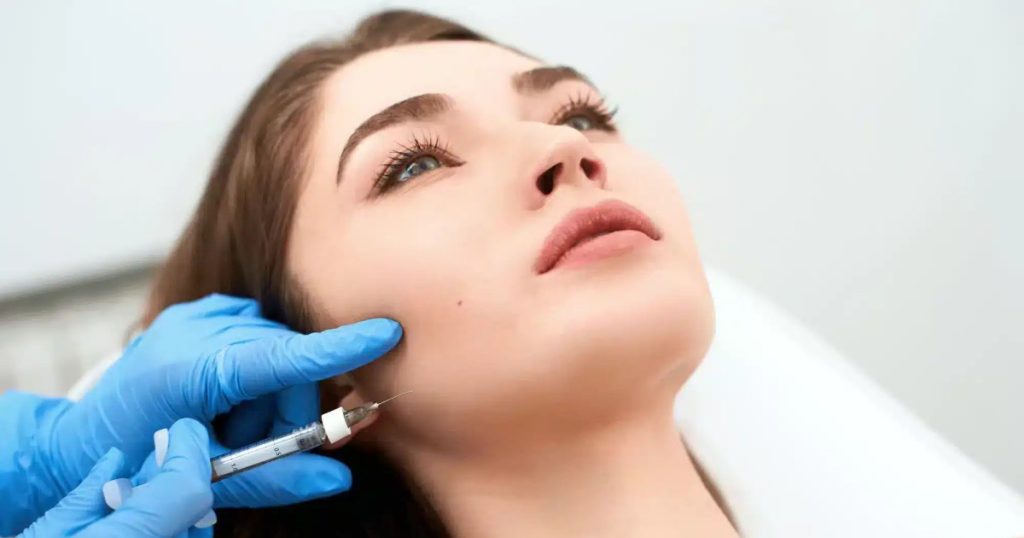 Close-up of a female patient lying in a dental chair while receiving TMJ Botox injections.