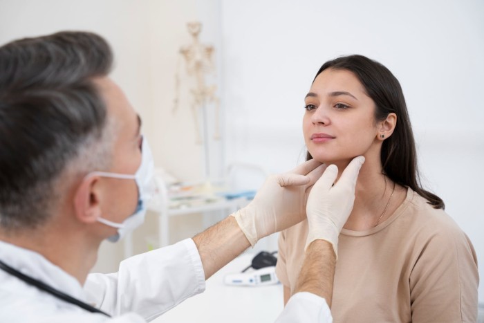 A male dentist evaluating a female patient's jaw for TMJ disorder to prepare a Letter of Medical Necessity for insurance purposes.